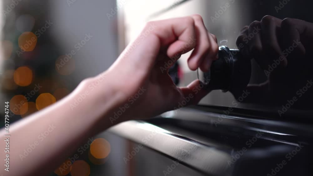 Boy's hand rolling oven knob in kitchen at home. Unrecognizable Caucasian child adjusting turning on or off device indoors. Cooking and baking.