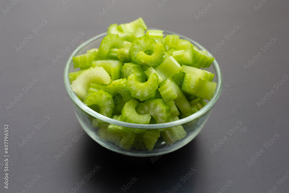 Celery slices in glass bowl on dark background. Celery slices in glass bowl on dark background.