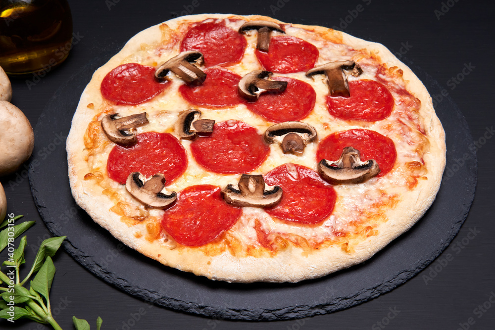 mushroom and pepperoni pizza made with mozzarella cheese on a black stone plate with a black background. mushroom and pepperoni pizza made with mozzarella cheese on a black stone plate with a black background.