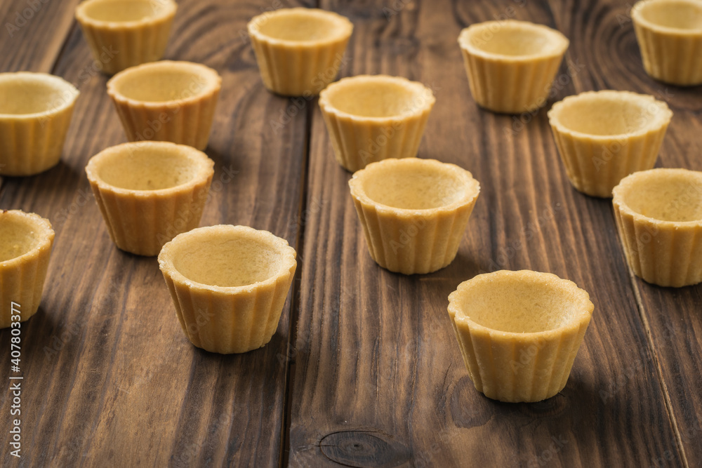 Empty tartlets arranged on a wooden table. Empty tartlets arranged on a wooden table.