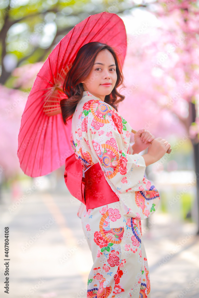 Portrait of a traveler young asian woman wear a dress yukata and walking on tree path in japan cherry blossoming sakura park at sunlight afternoon. Portrait of a traveler young asian woman wear a dress yukata and walking on tree path in japan cherry blossoming sakura park at sunlight afternoon.