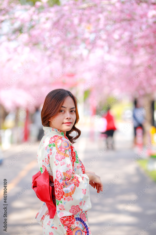 Portrait of a traveler young asian woman wear a dress yukata and walking on tree path in japan cherry blossoming sakura park at sunlight afternoon. Portrait of a traveler young asian woman wear a dress yukata and walking on tree path in japan cherry blossoming sakura park at sunlight afternoon.