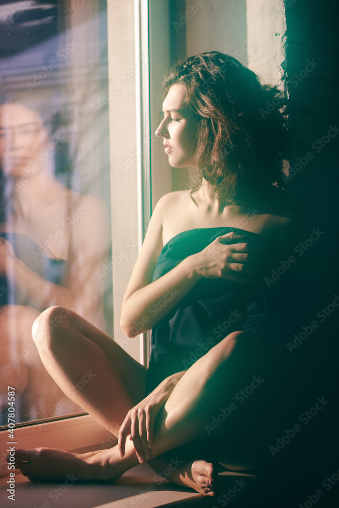 Girl in a jacket on a naked body sitting on a window sill. High quality photo