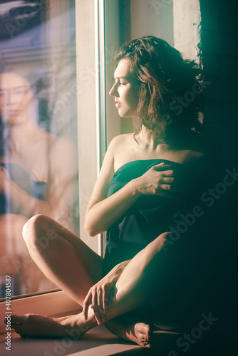 Girl in a jacket on a naked body sitting on a window sill. High quality photo
