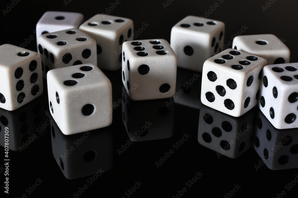 A close up image of several white dice on a black reflective table top. A close up image of several white dice on a black reflective table top.