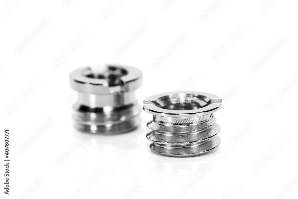 Two shiny threaded metal inserts on white background