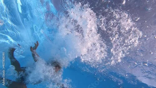 The child is floating under water.
A young boy swims underwater in a clean pool. Underwater shot. Slow motion.
