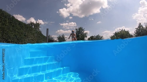 The child is floating under water.
A young boy swims underwater in a clean pool. Underwater shot. Slow motion.