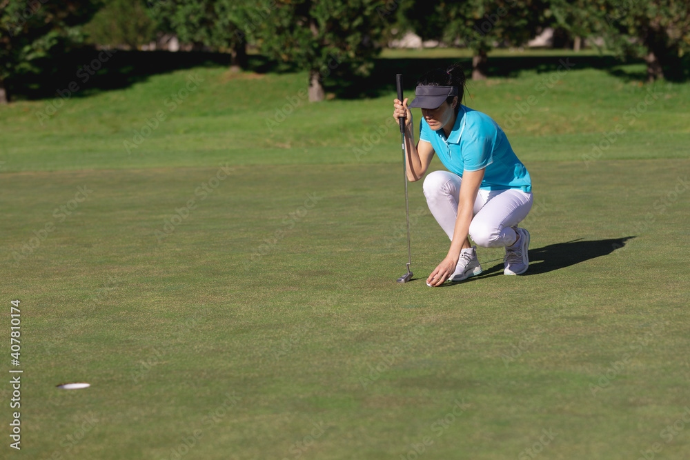 Caucasian woman playing golf placing ball before taking shot at hole Caucasian woman playing golf placing ball before taking shot at hole