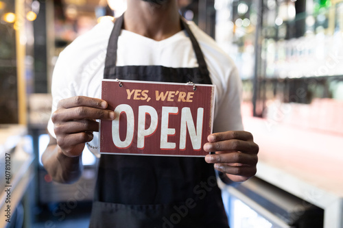 Portrait of african american male barista holding a were open card