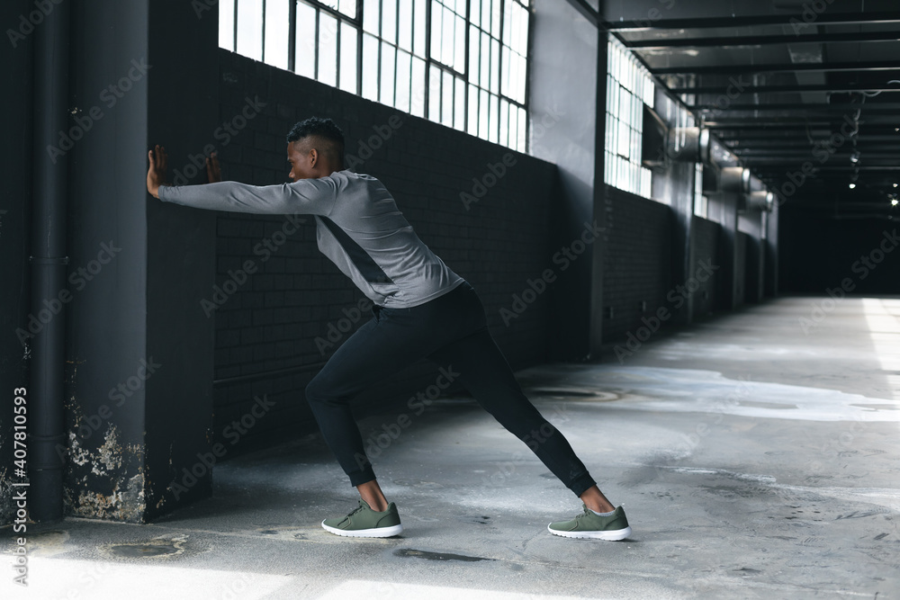 African american man leaning on a wall in an empty urban building and stretching African american man leaning on a wall in an empty urban building and stretching