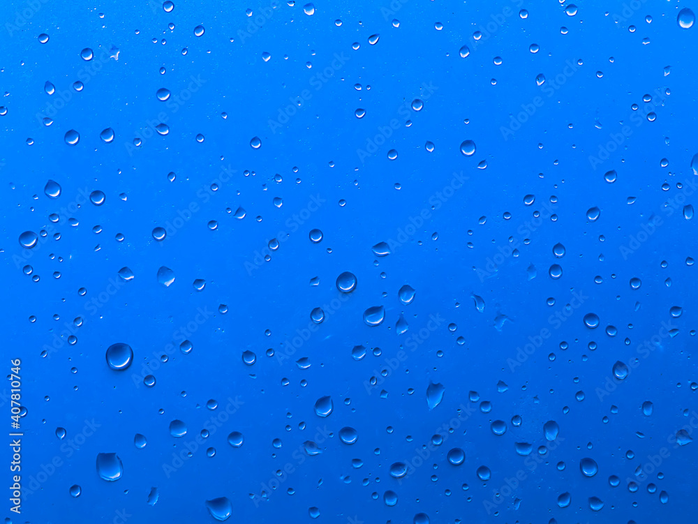 Defocused water drop on glass background with blue color.