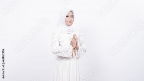 Asian muslim woman wearing prayer beads welcoming guests / Ied Fitr Greeting in white background © HumbaFrame