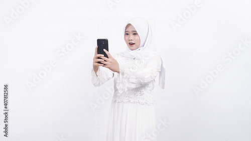 Asian muslim woman wearing prayer beads holding blank screen phone in white background