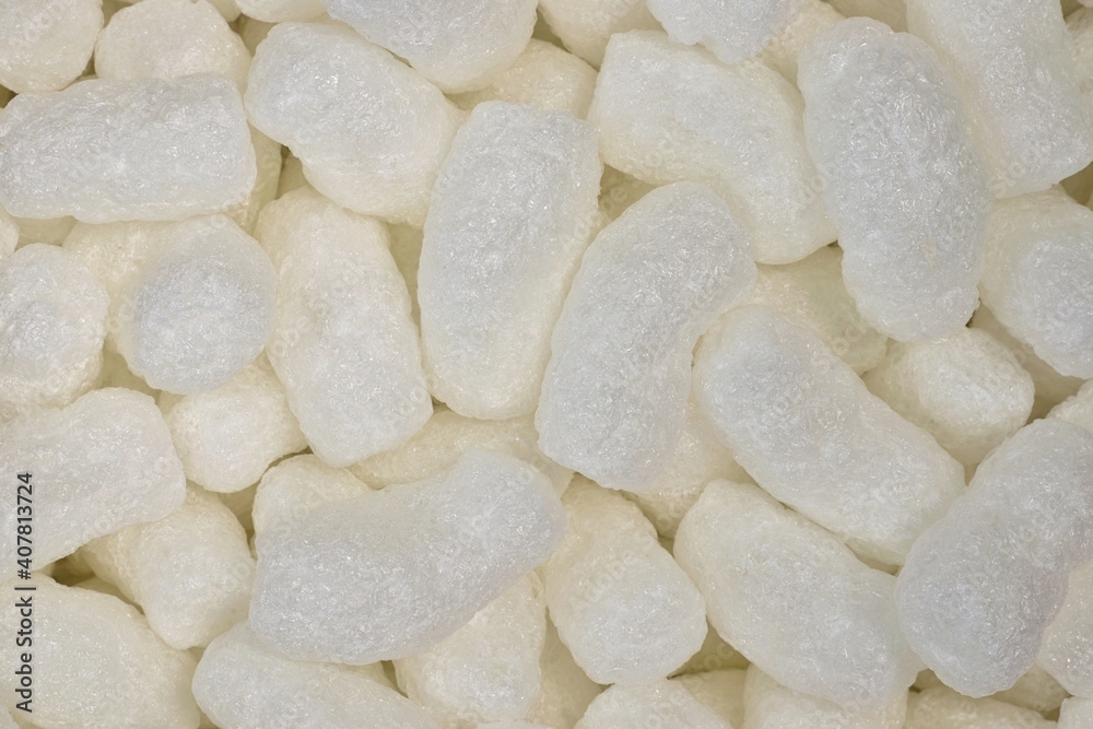 White protective packing peanuts styrofoam popcorn packaging material used in shipping boxes, closeup flat lay.