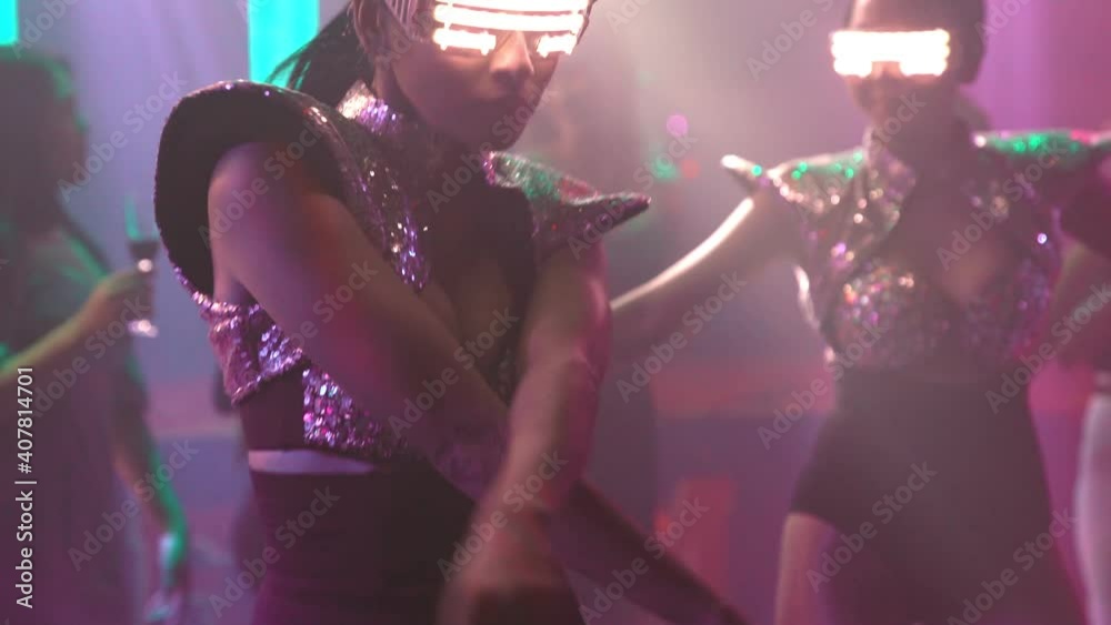 Group of people dance in disco night club to the beat of music from DJ on stage . New year night party and nightlife concept .
