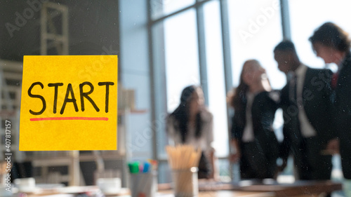 Close up yellow start text post it note on the glass with business people meeting at the background.