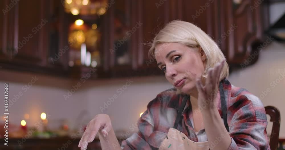 Portrait of blond beautiful Caucasian woman tossing flour sitting in kitchen at home. Tired young charming lady cooking baking indoors. Lifestyle and boredom. Cinema 4k ProRes HQ. Portrait of blond beautiful Caucasian woman tossing flour sitting in kitchen at home. Tired young charming lady cooking baking indoors. Lifestyle and boredom. Cinema 4k ProRes HQ.