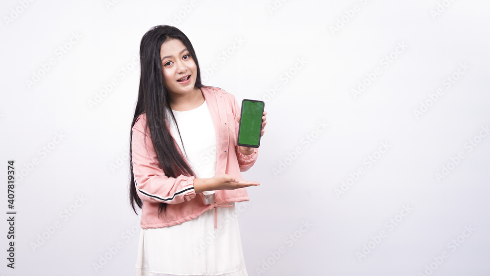 Fototapeta premium beautiful asian woman pointing green screen in handphone isolated white background