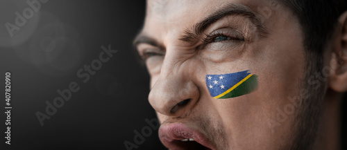 A screaming man with the image of the Solomon Islands national flag on his face