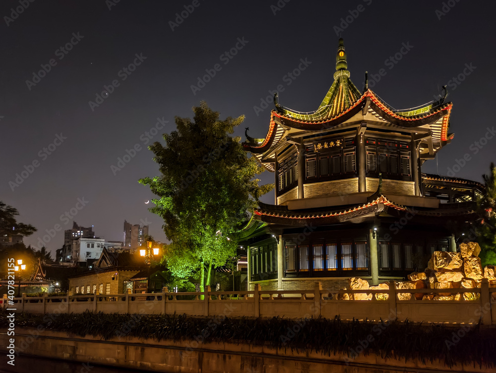 Fototapeta premium Illuminated pagoda in an Asian historical ancient style park, night shot 