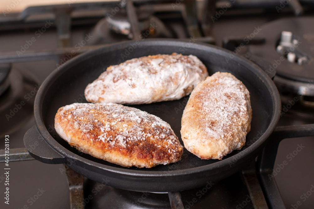 Semi finished frozen cutlets. Frozen cutlets in a frying pan. Concept of storing ready made dinner