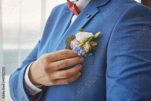 bride adjusts the boutonniere on his suit. preparing for the wedding.