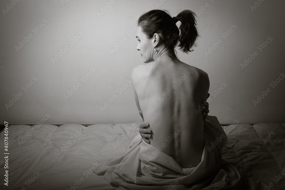Conceptual image of a woman sad and lone on a bed under a sheet Conceptual image of a woman sad and lone on a bed under a sheet
