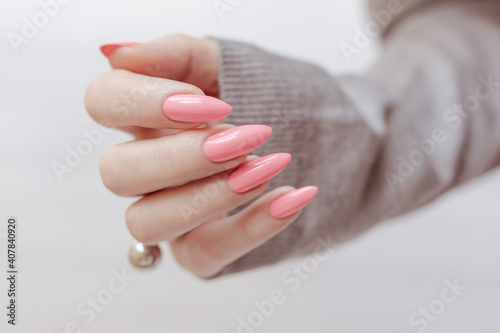 Obraz na płótnie Female hand with long nails and a bottle of bright pink neon nail polish