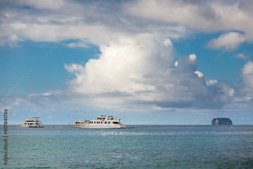 Beautiful landscape with cruise ships under dramatic blue sky and clouds. Vacation travel to exotic tourist attractions. Daphne Minor of Galapagos Islands, Ecuador, Pacific Ocean