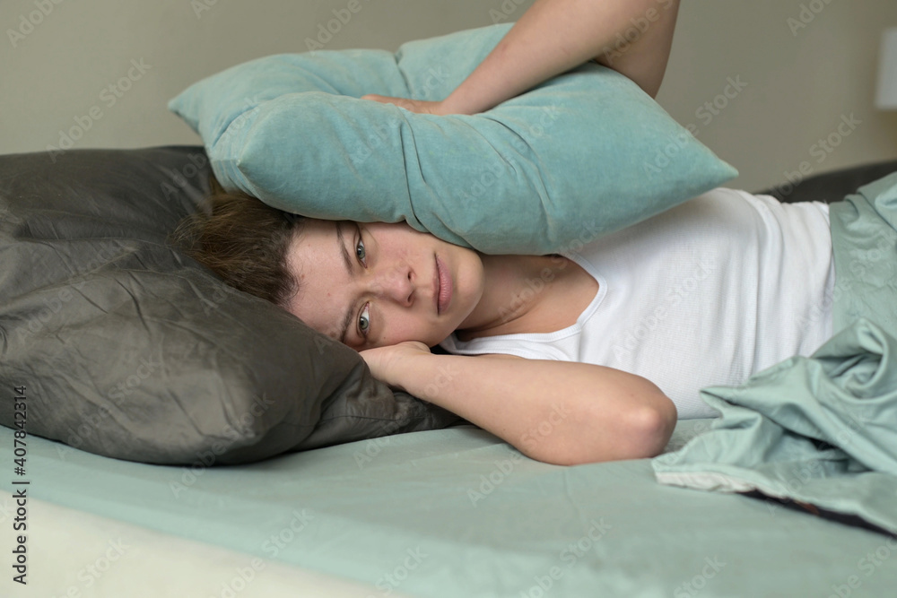 woman is woken up and annoyed by noise from neighbors or from the street woman is woken up and annoyed by noise from neighbors or from the street