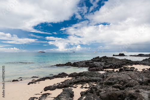 Beautiful tropical beach under dramatic blue sky with a cruise ships in the background. Vacation adventure at exotic travel destination. Popular tourist attraction. Santa Cruz. Galapagos islands.