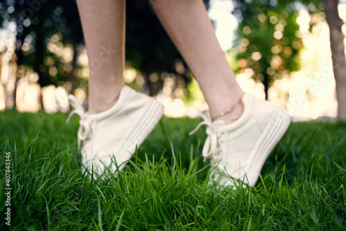 Female legs white sneakers green grass walk outdoors