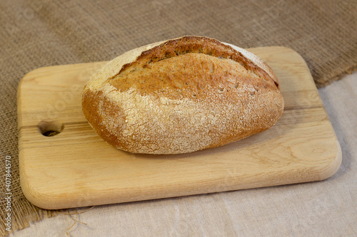 Appetizing freshly baked bread with a golden brown crust on wood cutting board a rough linen cloth close-up