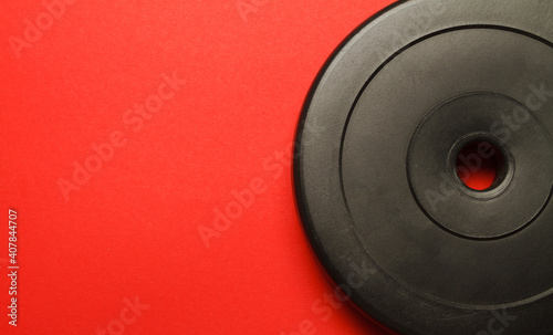 Dumbbell weight plate on red background with copyspace.