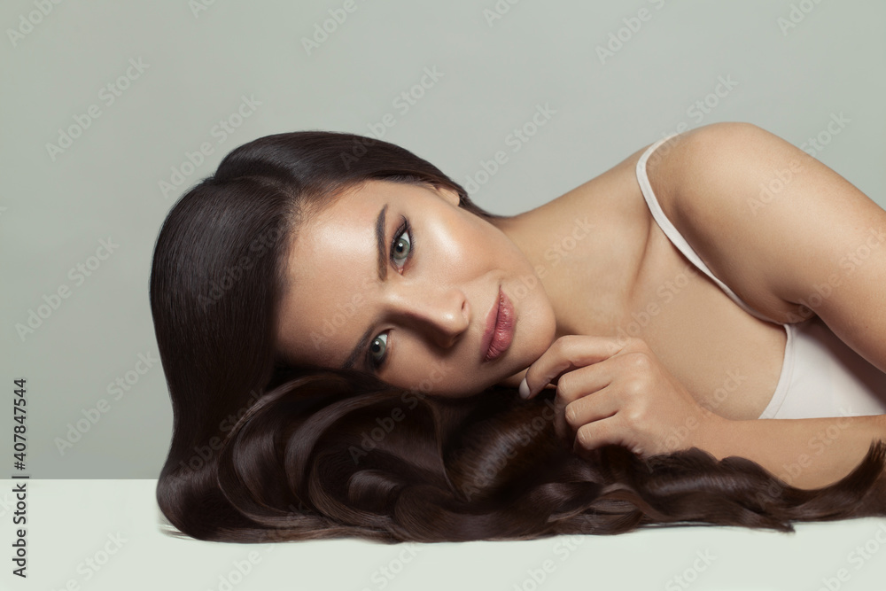 Naklejka premium Young perfect woman with healthy hair and clear shiny skin on white background. Haircare and facial treatment concept
