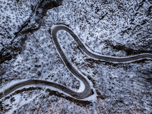 Road with curves and hairpin bends in a snowy forest