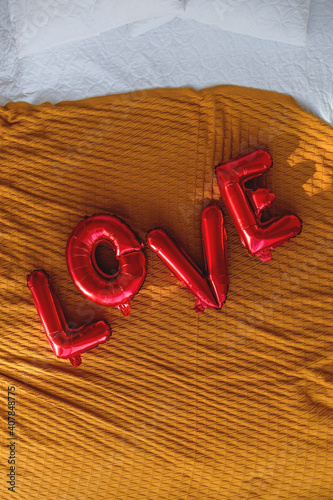 Red balloons in the shape of the lettering love on the bed. Valentines day concept