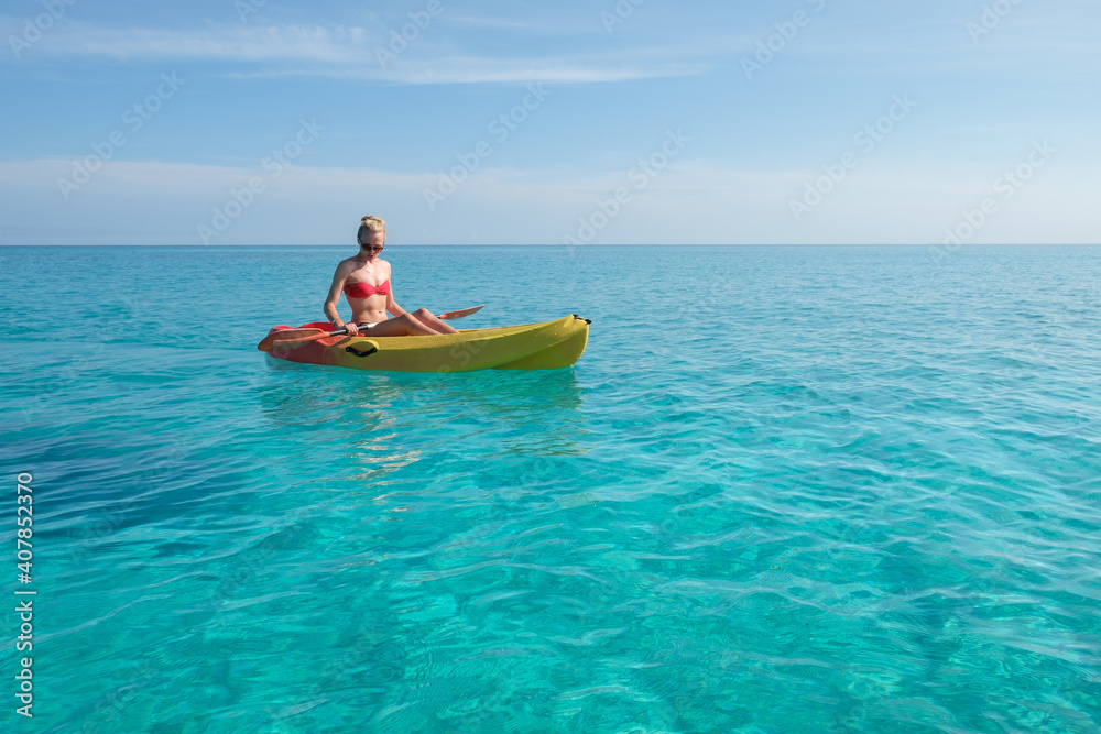 girl paddles a kayak in the turquoise waters, vacation in Cuba
