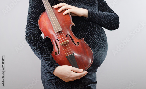Pregnant woman with red violin isolated on gray background.