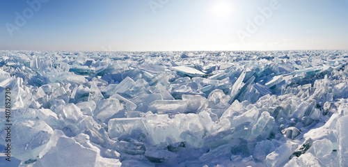 Panoramic view on endless hummock field on the frozen Lake Baikal. Piles of snow-covered debris of blue ice on a sunny frosty day. Cold natural background. Unusual winter landscape