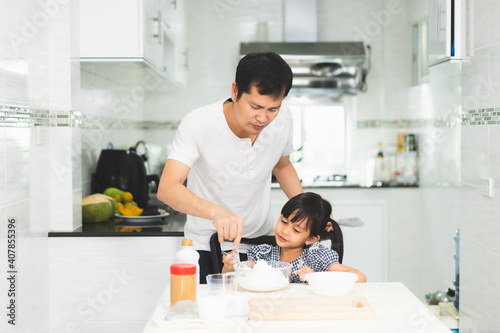 Asian father and little daughter are preparing and cooking together in the kitchen for home learning activity for kids, concept of family lifestyle and parent and child working for development.