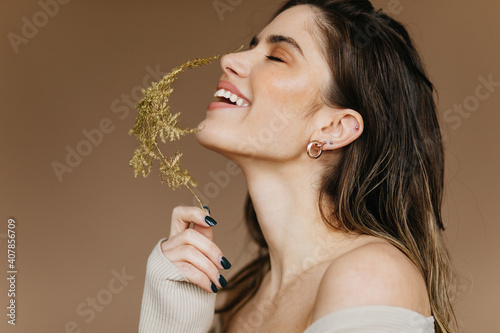 Laughing good-humoured girl holding plant. Fashion photo of attractive lady with flower. photo