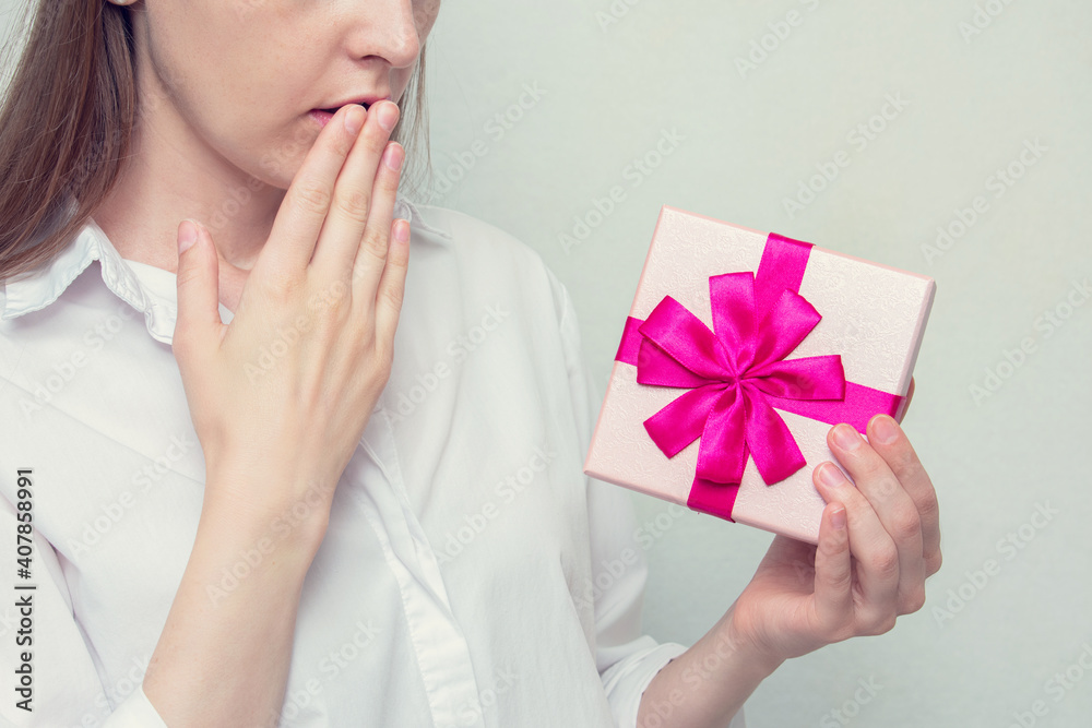 Puzzled girl with gift box, white background, concept of bad gifts for holidays, cropped image Puzzled girl with gift box, white background, concept of bad gifts for holidays, cropped image