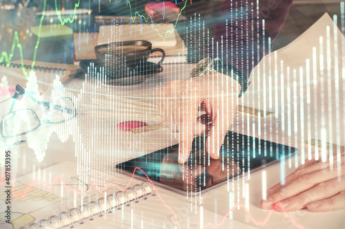 Double exposure of man's hands holding and using a digital device and forex graph drawing. Financial market concept.