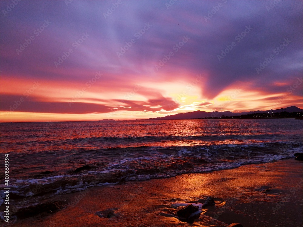 Obraz premium Atardecer teñido de rojo, mar colorido con la luz del cielo.