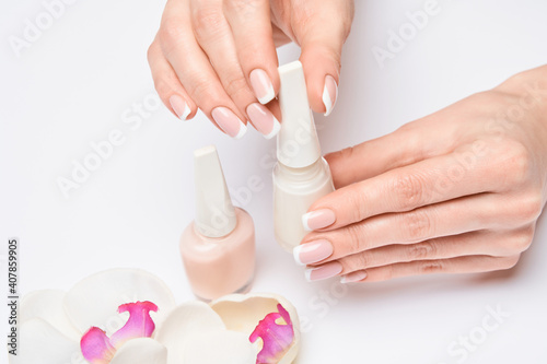 Beautiful Female Hands with French manicure over light grey background
