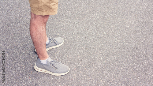 Person is about to take a step, asphalted street, feet in sneakers, close up, copy space, advertising, tonedб 16:9