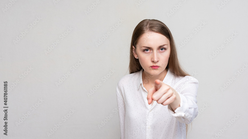 Portrait of a angry young woman pointing finger at you camera gesture, white background, 16:9 Portrait of a angry young woman pointing finger at you camera gesture, white background, 16:9