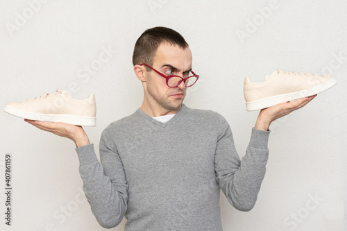 Unsatisfied nerd does not want to play sports, person shows his sneakers to the camera, white background photo